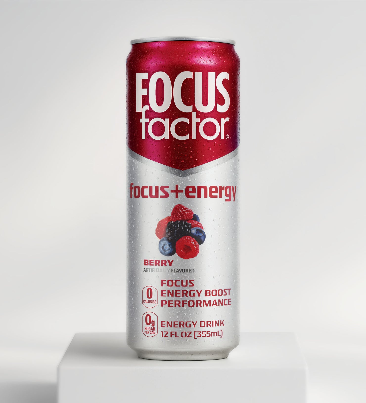 A 12 fl oz can of Focus + Energy Drink - Berry Flavor from Focus + Energy Drinks stands upright on a white platform. The red and silver can features berries, promotes nootropics for energy, and offers zero sugar.